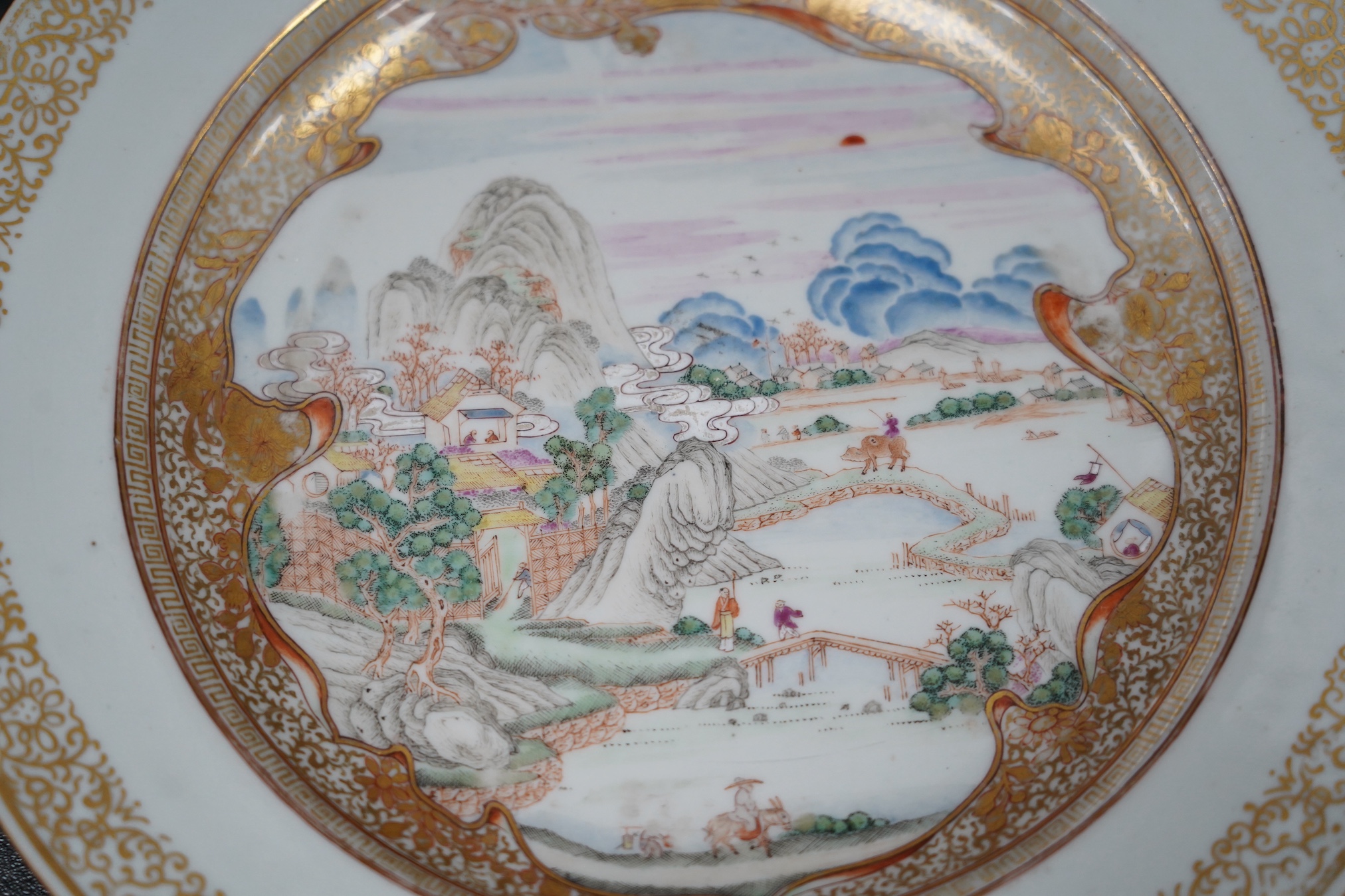 A pair of Chinese famille rose ‘landscape’ plates, Yongzheng-Qianlong period, small edge chip